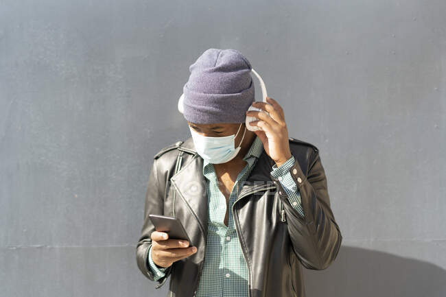 Jeune homme africain en ville écoutant de la musique depuis son smartphone — Photo de stock