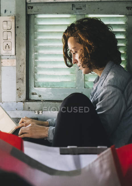 Jovem mulher europeia trabalhando em seu tablet enquanto viaja de Nova Deli a Agra em um trem de classe adormecido. — Fotografia de Stock