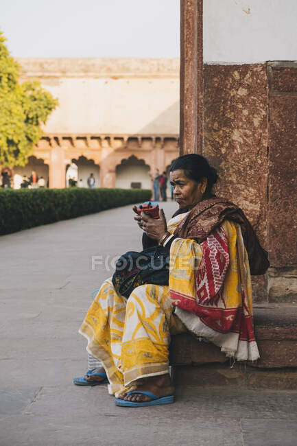 Indian woman playing with toy camera dressed in yellow sari at the Agra Fort Entrance. — Stock Photo