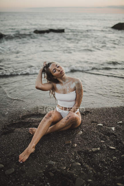 Молодая девушка позирует на пляже на закате — стоковое фото