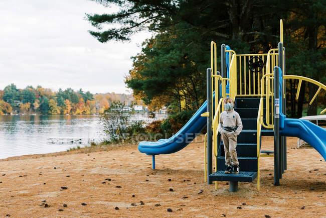 A boy at a playground with his face mask on — Stock Photo