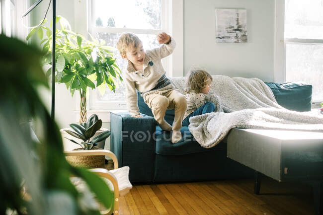 Двое детей играют вместе под одеялом в своей гостиной — стоковое фото