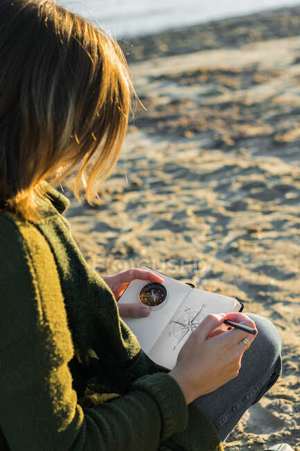 La giovane donna sta disegnando una bussola in un quaderno. Stile di vita, viaggi — Foto stock