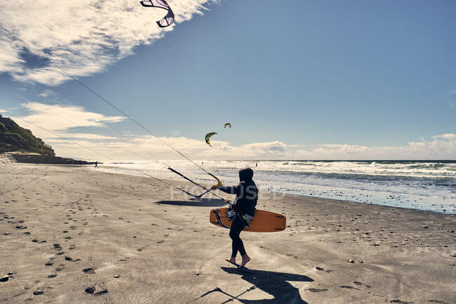 A kite surfer walks along a beach in Southern California, San Diego — Stock Photo