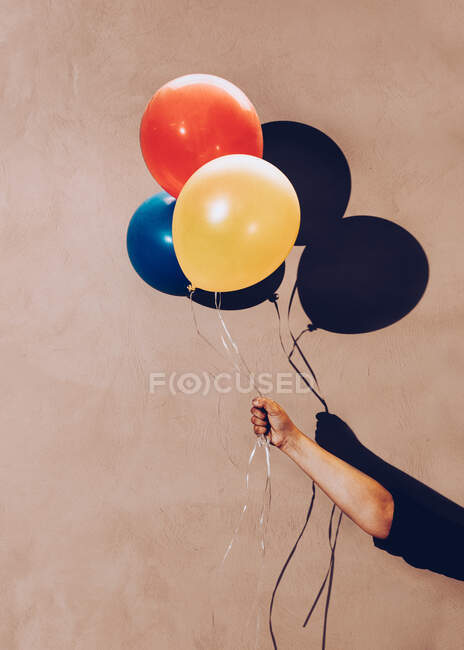 Balões nas mãos sobre o fundo da parede — Fotografia de Stock