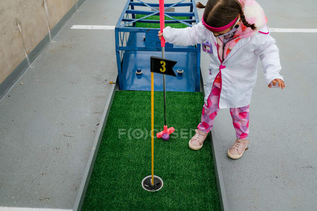 Menina pré-escolar em traje médico jogando mini golfe no dia das bruxas — Fotografia de Stock