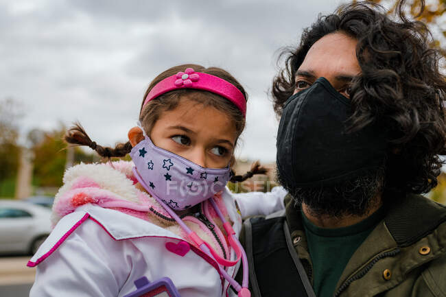 Father and daughter with protective face masks and halloween costume — Stock Photo