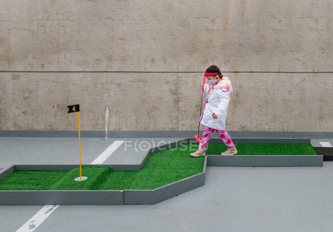 Mädchen im Arztkostüm spielt Minigolf auf Parkplatz — Stockfoto