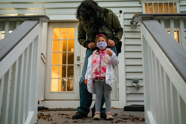 Father securing face mask on daughter before trick or treating COVID — Stock Photo