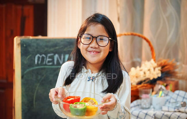 Дівчина показує їй приготований барвистий болгарський перець у скляній мисці — стокове фото