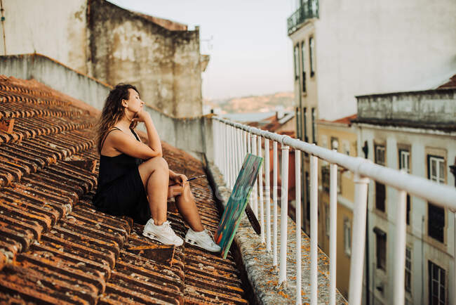 Pittore donna seduta sul tetto con tela d'arte astratta — Foto stock