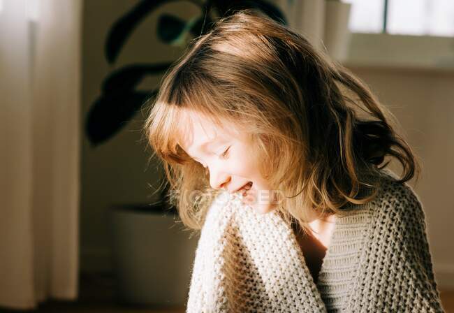 Retrato de una joven sentada en casa al atardecer sonriendo - foto de stock