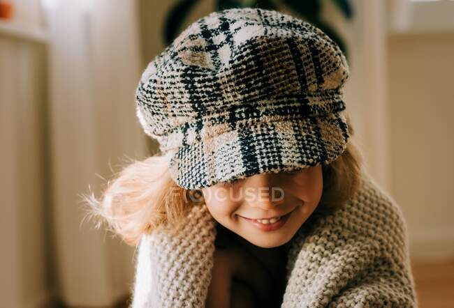 Ritratto di una giovane ragazza con un cappello su giocosamente sorridente a casa — Foto stock