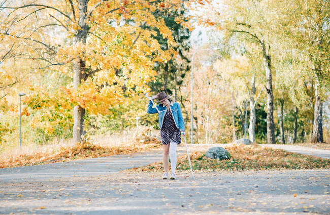 Injured woman walking with crutches with the wind blowing in fall — Stock Photo