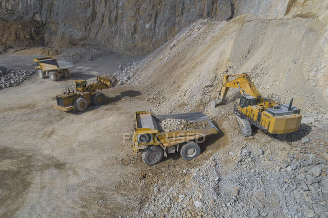 Loaders loading mining trucks at open pit — Stock Photo