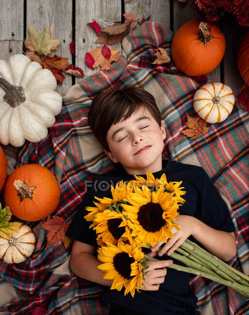 Visão aérea do menino segurando girassóis cercado por itens de outono. — Fotografia de Stock