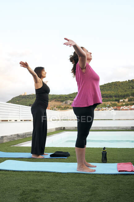 Deux femmes pratiquent le yoga sur la terrasse de la maison en plein air — Photo de stock