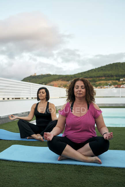 Two women practicing yoga on the terrace of the house, lotus posture — Stock Photo