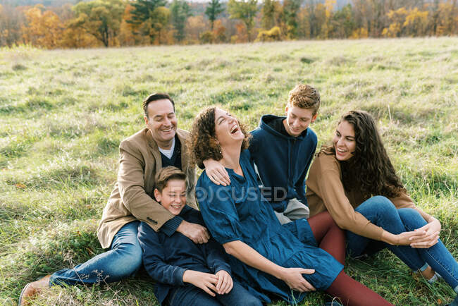 Uma família feliz de cinco pessoas sentadas juntas em um campo — Fotografia de Stock