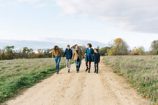 A happy family of five holding hands together on a path — Stock Photo