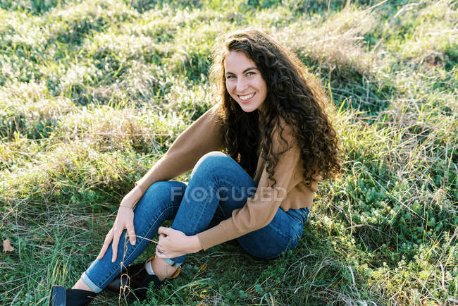 Glückliches Teenager-Mädchen sitzt in einem Feld aus hohem Gras — Stockfoto