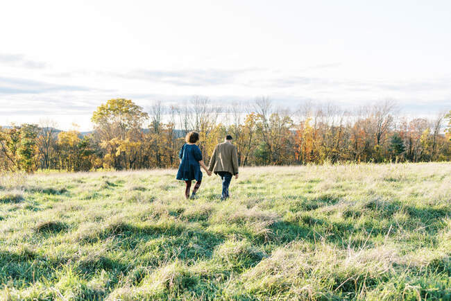 A couple walking in a field together during sunset in fall — Stock Photo