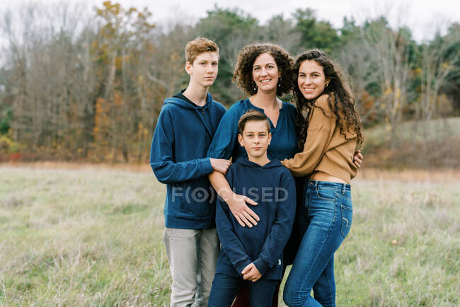 Щаслива мати і троє її дітей стоять разом у полі — стокове фото