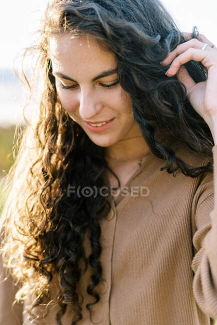 Portrait d'une adolescente heureuse avec les cheveux bouclés à l'extérieur pendant le coucher du soleil — Photo de stock