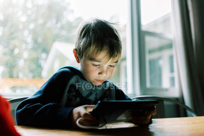 Petit garçon jouant à des jeux vidéo sur sa tablette — Photo de stock