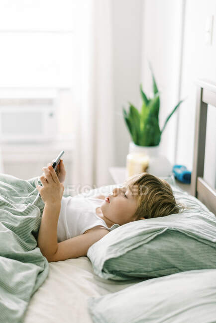 Ragazzino svegliarsi al mattino giocando il suo tablet — Foto stock