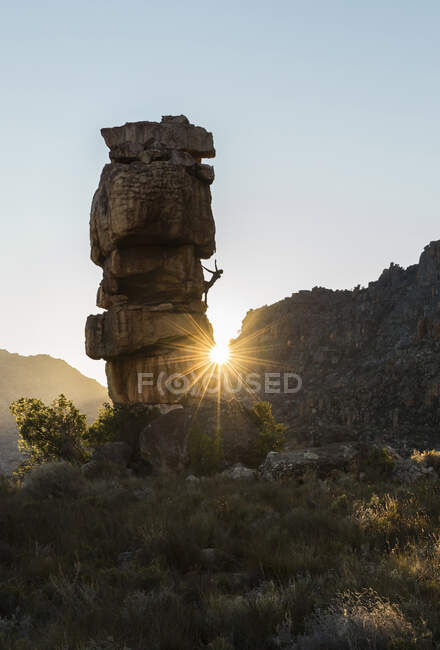 Homme athlétique grimpe dehors sur un rocher avec des rayons de soleil — Photo de stock