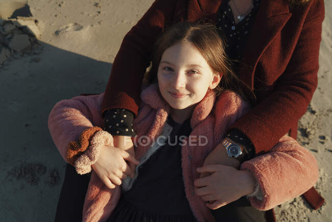 Retrato de menina com as mãos da mãe na praia de areia — Fotografia de Stock