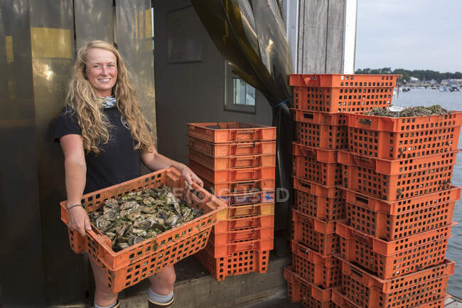 Female shellfish farmer holding crate of oysters — Stock Photo