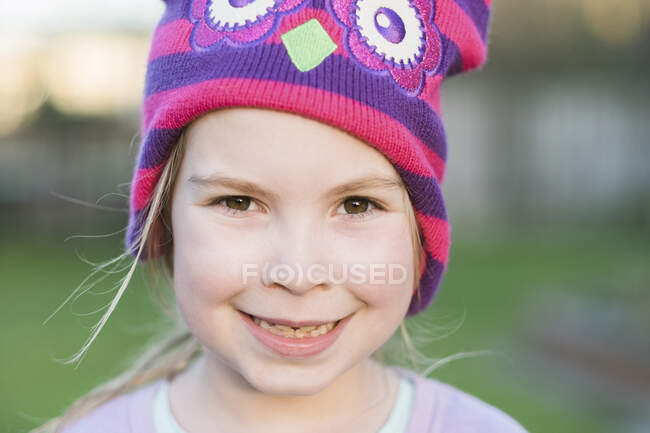 Fechar-se de uma menina sorrindo e vestindo um chapéu colorido — Fotografia de Stock