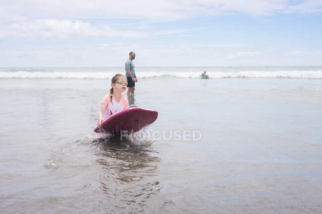Junges Mädchen mit Brille hält Boogie Board am Strand — Stockfoto
