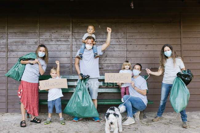 Группа семей добровольцев в медицинских масках и с мусором в руках — стоковое фото