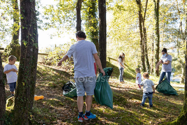 Група волонтерських сімей, що збирають сміття в лісі на сонячний день — стокове фото