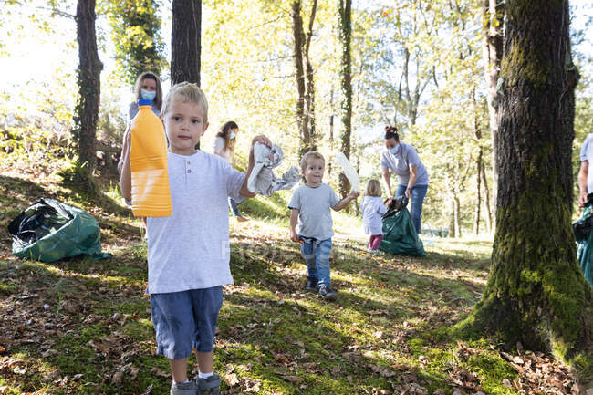 Enfants bénévoles ramassant des ordures avec leurs familles dans — Photo de stock