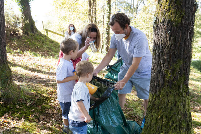 Voluntarios niños recogiendo basura junto con sus familias - foto de stock