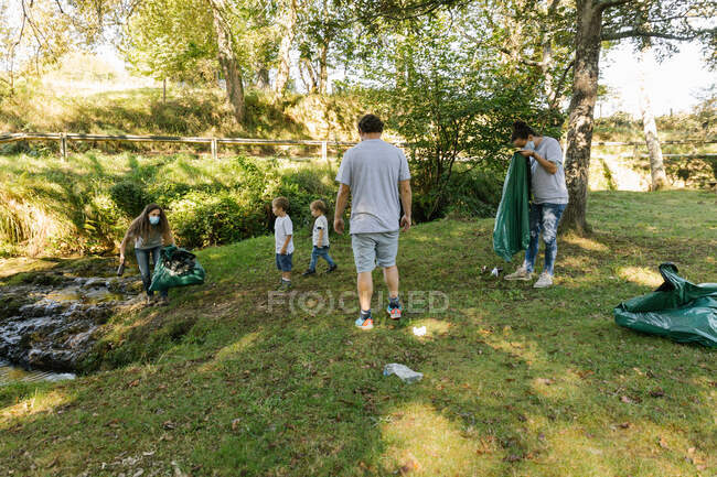Семья с детьми собирает мусор на берегу реки — стоковое фото