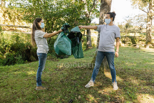 Пара добровольцев, держащих мусорные мешки в лесу. Концепция экологии — стоковое фото