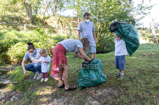 Gruppe ehrenamtlicher Familien sammelt Müll mit medizinischen Masken — Stockfoto