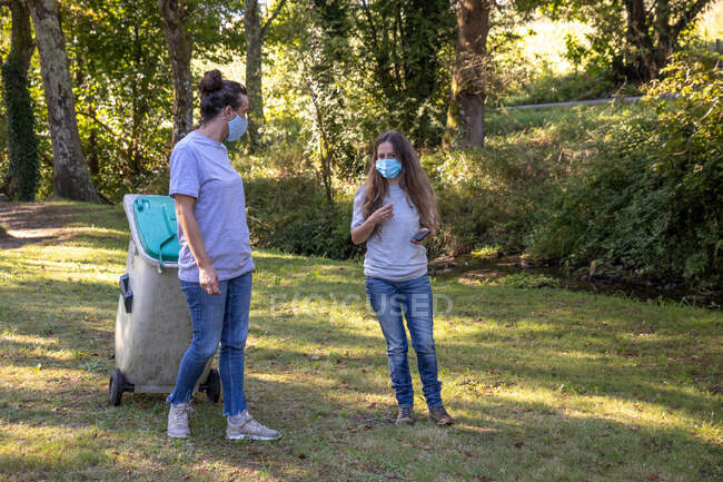 Волонтеры в медицинских масках собирают мусор в природном парке — стоковое фото