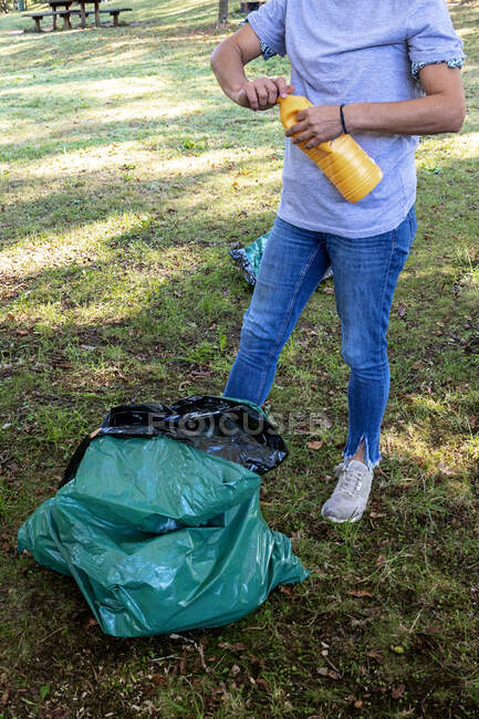 Волонтёр собирает пластиковые бутылки для переработки в природном парке. — стоковое фото