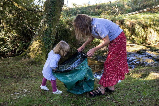 Волонтерка мати з дочкою тримає мішок для сміття — стокове фото