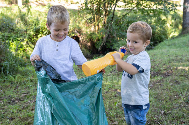 Дети-добровольцы собирают пластиковые бутылки с мешком для мусора — стоковое фото