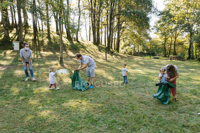Group of volunteer families collecting garbage in a natural park helpi — Stock Photo