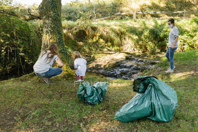 Добровольцы собирают мусор на берегу реки в солнечный день. — стоковое фото