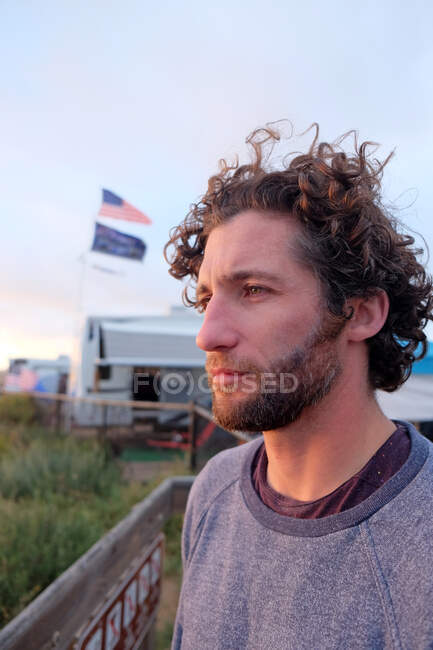 Homme avec des cheveux bouclés dans le profil regardant pensivement à l'océan — Photo de stock