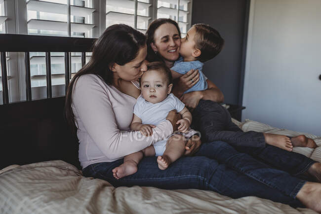 Glückliche nicht-traditionelle Familie mit zwei Müttern und Kindern, die zu Hause kuscheln — Stockfoto